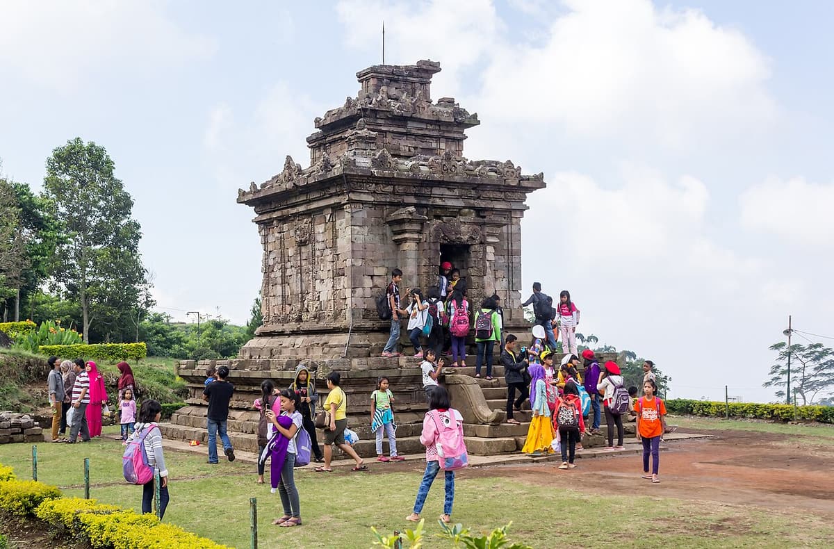A small stone Hindu temple at Gedong Songo with visitors on the steps