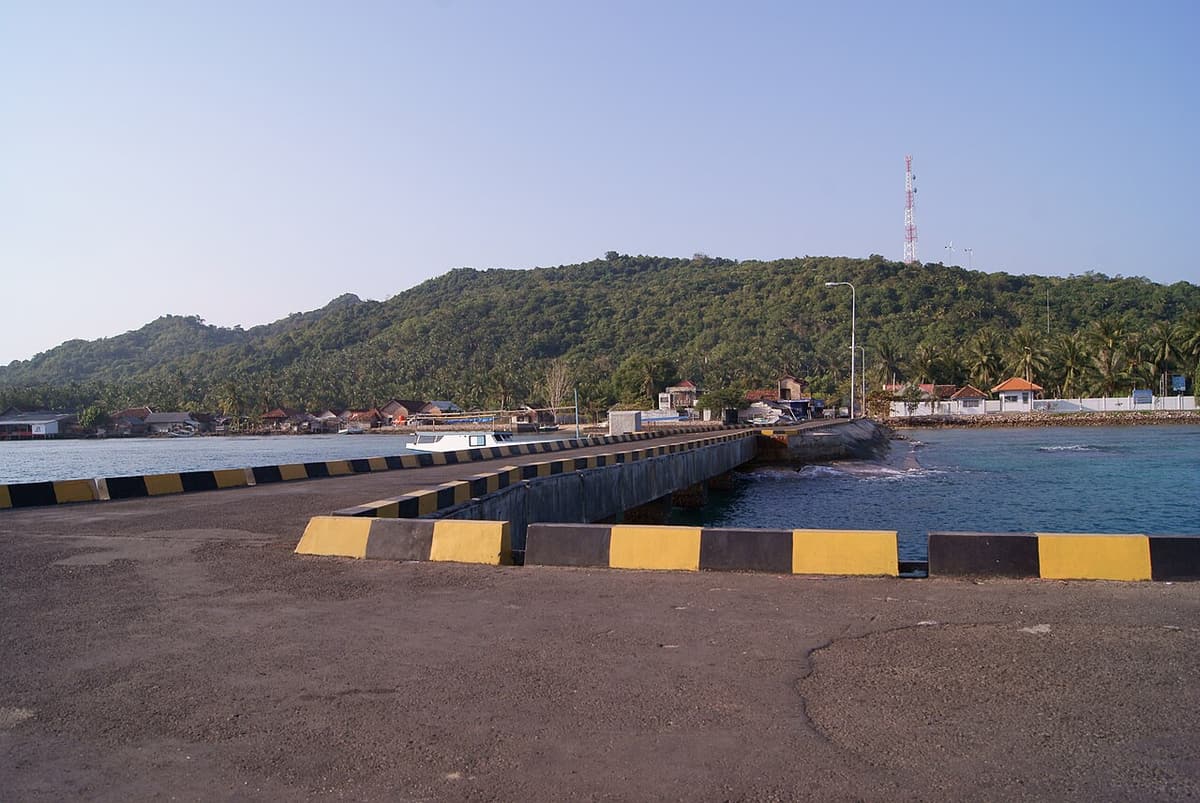 The concrete pier at Karimunjawa harbour with green hills behind
