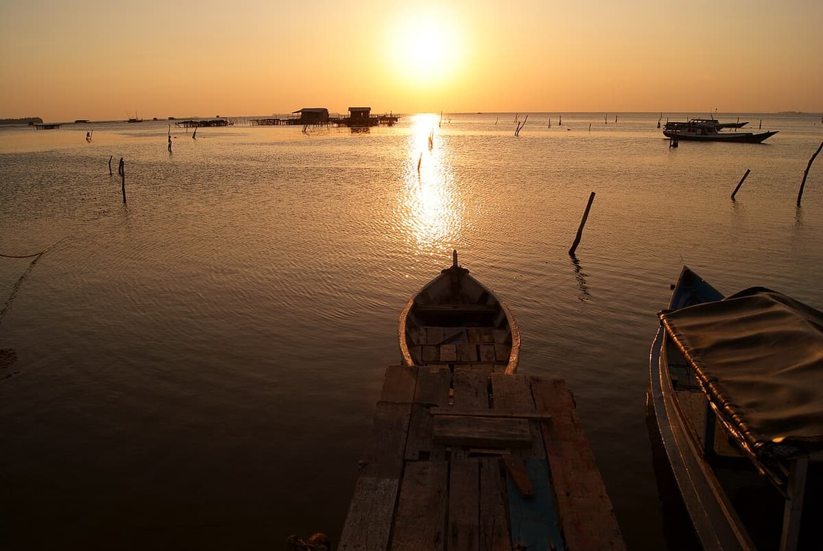 Wooden boats moored in calm water at sunset at Karimunjawa’s old harbour